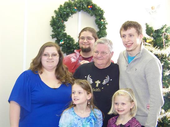 A joyful family poses together for a holiday portrait surrounded by festive decorations.