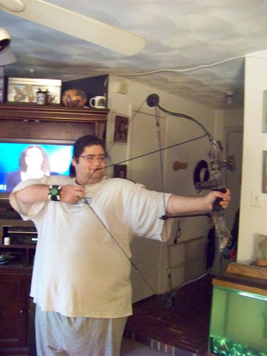Individual aims with a bow, focusing on target practice inside a warm living room environment.