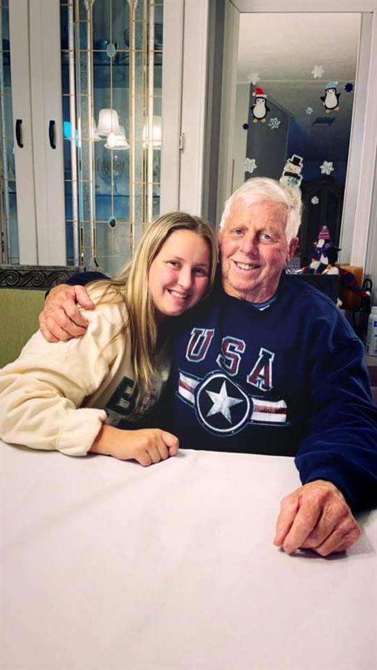 Grandfather and granddaughter enjoy quality time together while smiling and embracing at home.