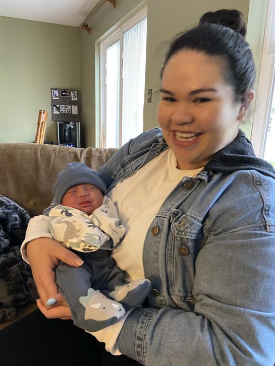 A joyful mother cradles her newborn, showcasing love and warmth in a comfortable setting at home.