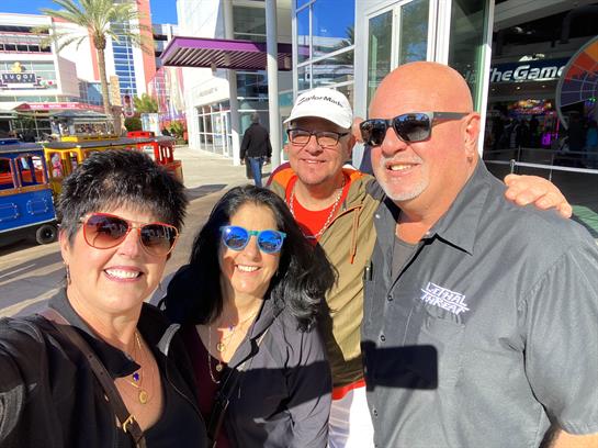 Four friends gather and smile for a cheerful group photo in a bustling Las Vegas area.