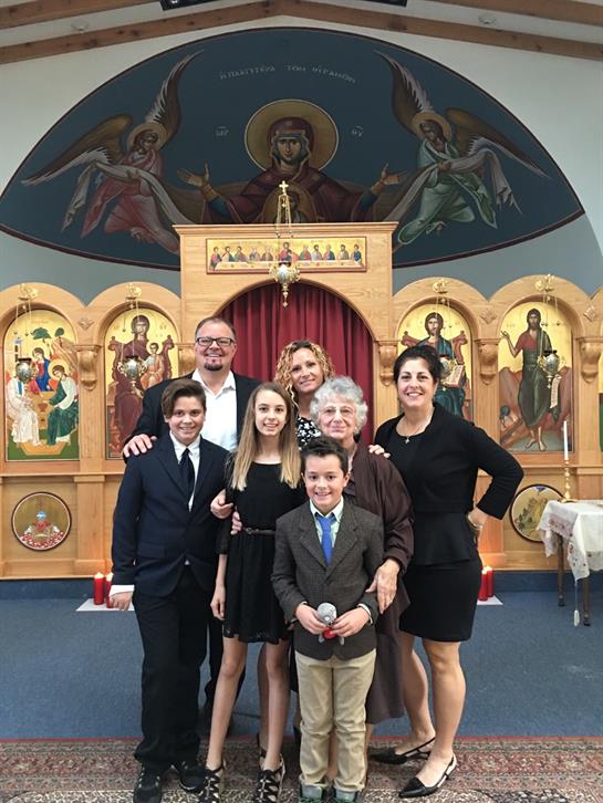 A family gathers with smiles to celebrate a special occasion in a church adorned with icons.