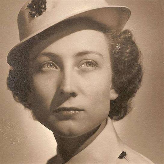 A woman wearing a uniform hat poses with a serious yet elegant demeanor in a vintage setting.