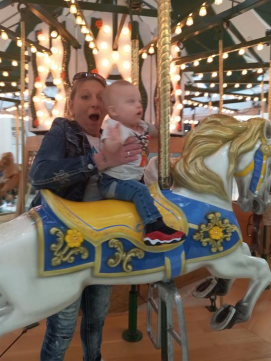 A child and adult enjoy a joyful moment on a carousel, surrounded by colorful lights.