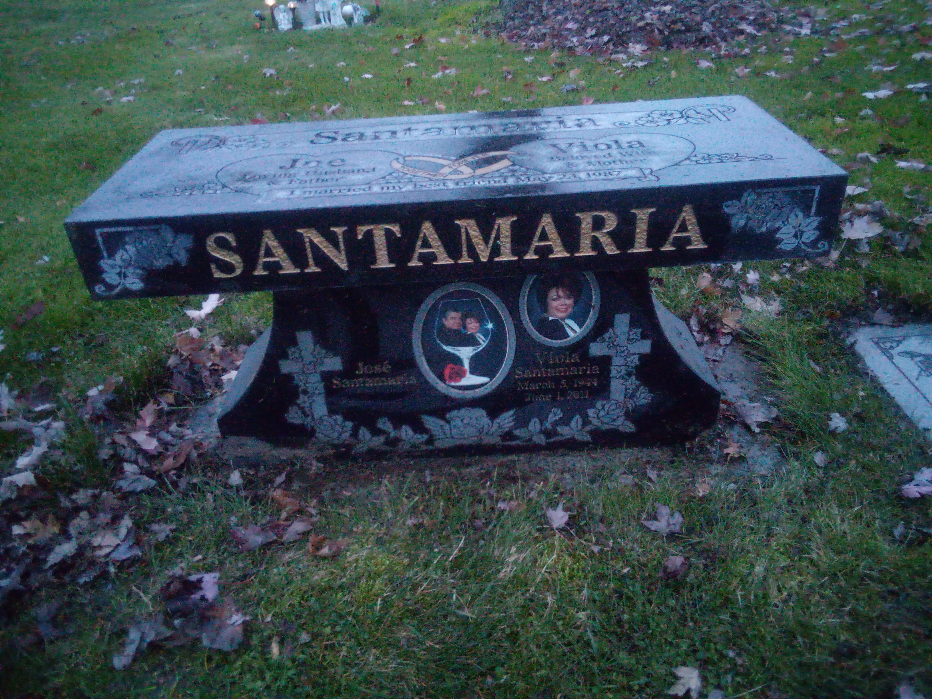 A memorial bench honoring the Santamaria family sits in a peaceful grassy area during twilight.