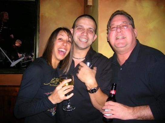 Three friends share laughter and drinks while celebrating together in a vibrant bar atmosphere.