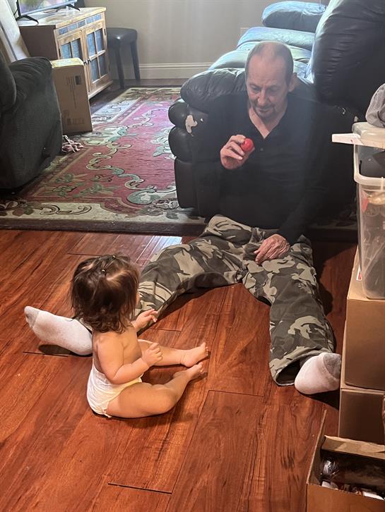 A man and a toddler share a joyful moment in a cozy living room as they engage in play.