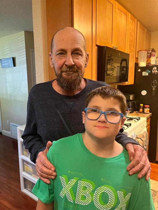 A joyful moment between a grandfather and his grandson in a warmly lit kitchen.