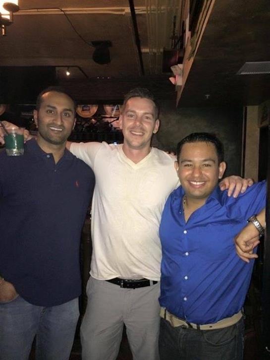 Three friends pose together at a bar, showcasing smiles and camaraderie during their night out.