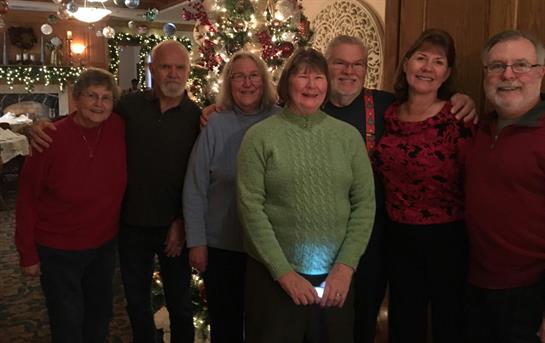 Friends and family pose together in a warmly decorated space, celebrating the holiday season.