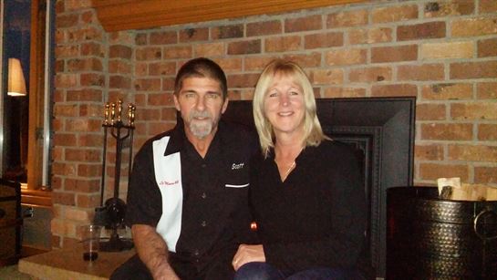 A man and woman sitting in front of a brick wall
