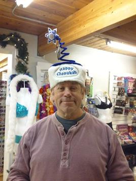 A man stands in a store wearing a humorous holiday hat, showcasing seasonal spirit and cheer.