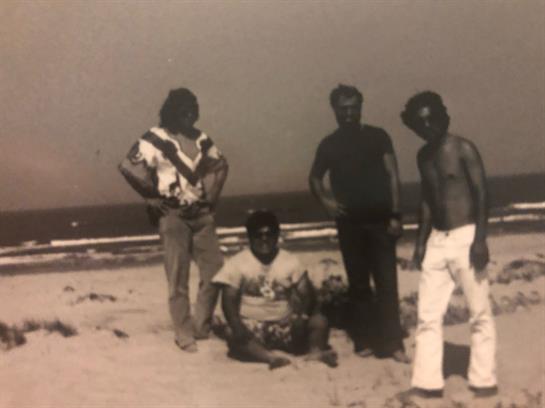Four friends gather on the sand, sharing laughs and enjoying the warm beach atmosphere.