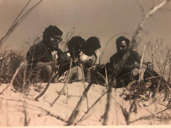 Friends gather on a sandy beach, soaking up the sun and relaxing as they share stories.