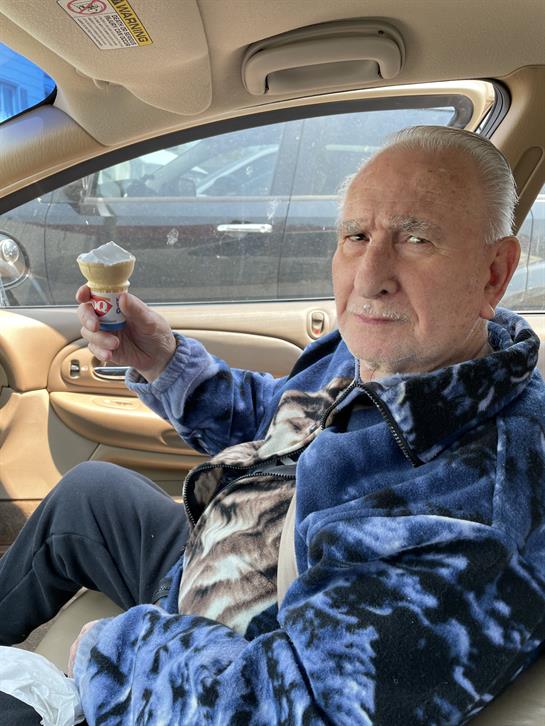 An old man in a car holding an ice cream cone