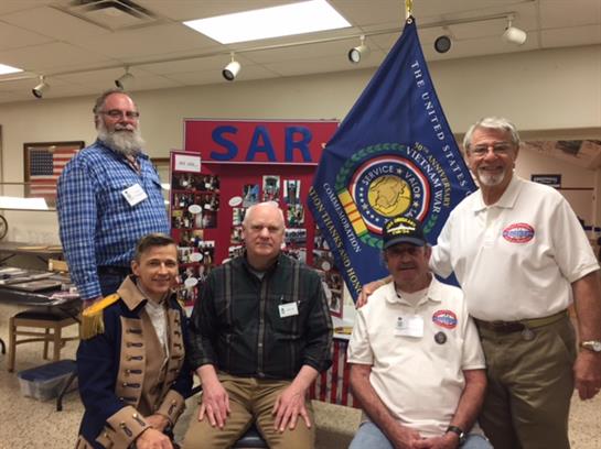 Group of individuals dressed in historical attire participates in a community event.