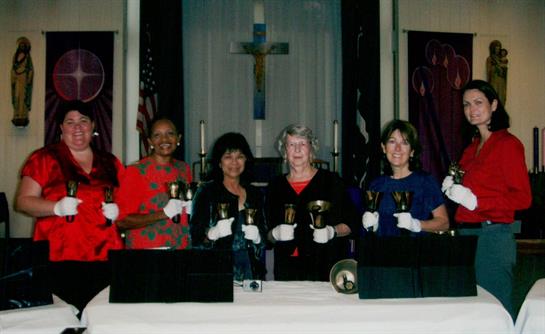Five women are joyfully ringing handbells together at a church during a community event.
