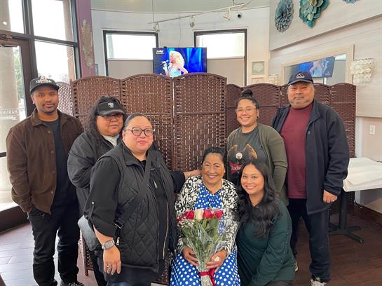 A group joyfully celebrates a special occasion with flowers at a restaurant.