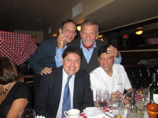 A group of friends enjoys a lively dinner in a warm restaurant atmosphere with laughter.