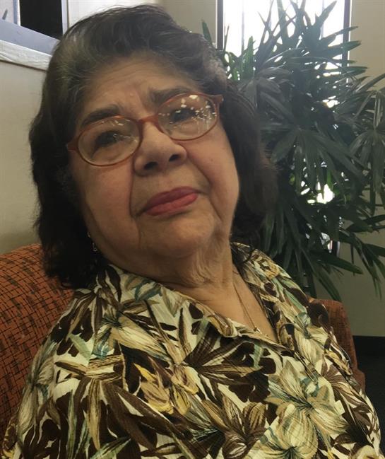 An elderly woman with glasses enjoys a warm moment while seated in a comfortable area.