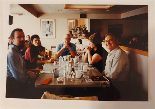 Five friends share laughter and conversation over breakfast in a lively cafe atmosphere.