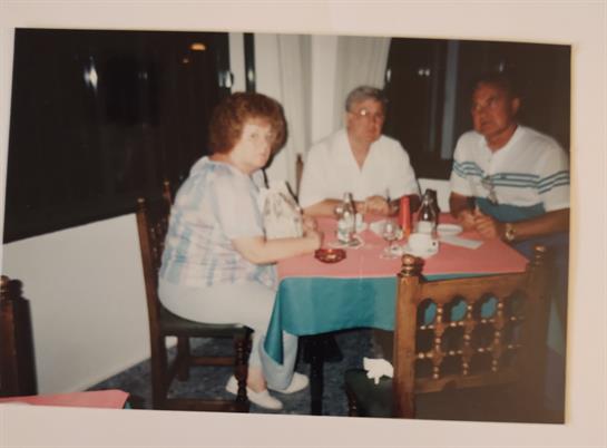 Three friends are seated around a table enjoying a meal together in a comfortable restaurant.