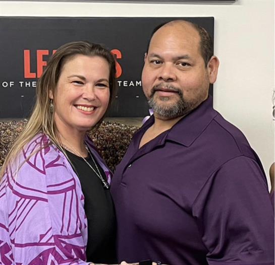 A couple smiles joyfully together in a friendly space filled with motivational quotes.