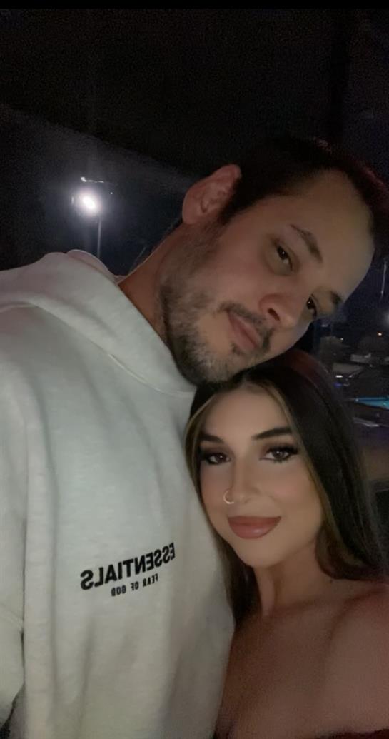 A couple shares a loving moment in a vibrant and warmly lit setting during the night.