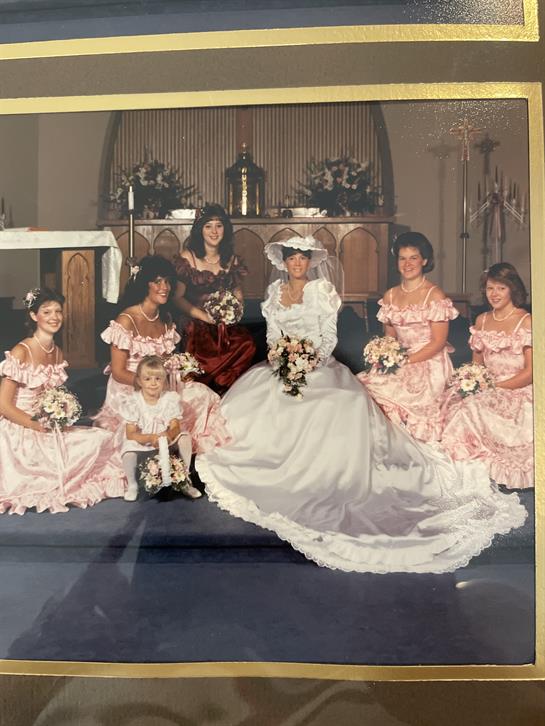 Seven bridesmaids and a flower girl pose with the bride in a church adorned with flowers.