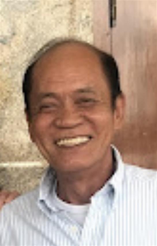 A cheerful elderly man is seen smiling broadly in a relaxed environment with soft light.