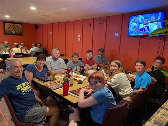 A lively group gathers around tables to share food and laughter in a cozy restaurant.