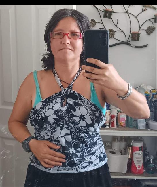 A woman poses for a selfie in a bathroom surrounded by various toiletries and decorations.