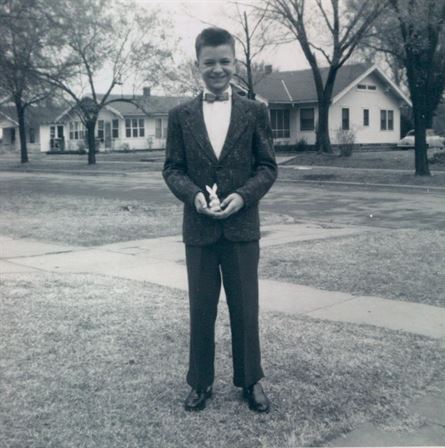 A man in a tuxedo standing in front of a house