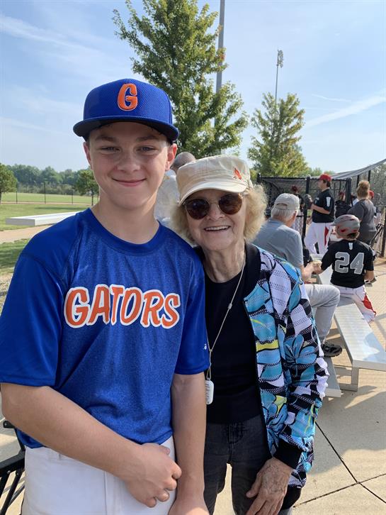 Young athlete poses proudly with his grandmother during a community baseball event.