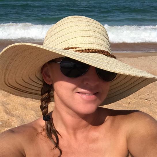 A woman wearing a hat and sunglasses on a beach