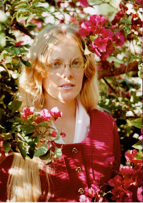 A woman in glasses standing in front of a flowering tree