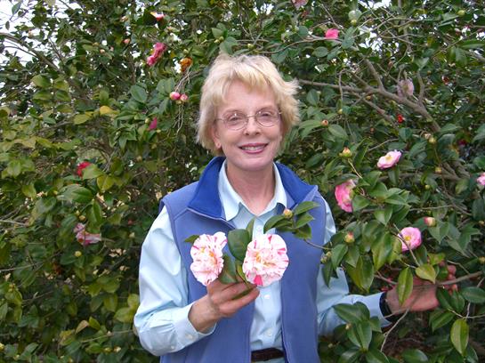 A woman holding flowers in front of a bush
