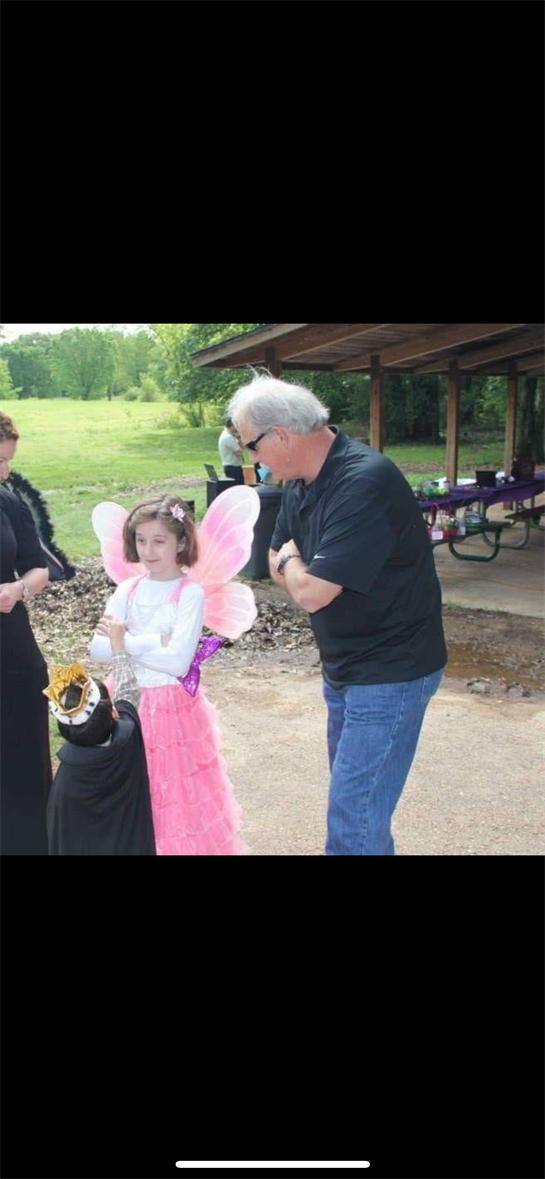 Kids dressed as a fairy and a character enjoy a joyful moment during an outdoor celebration.