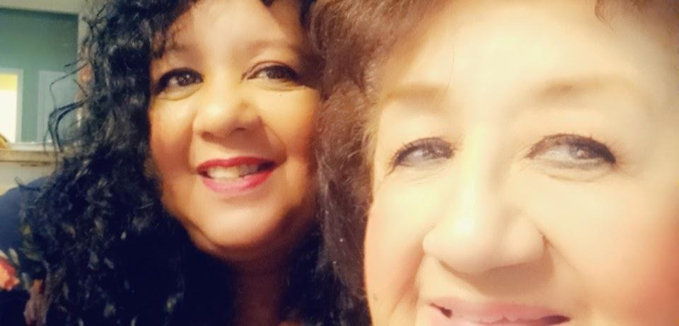 Two joyful women enjoy a cheerful moment together, showcasing their friendship in a warm atmosphere.