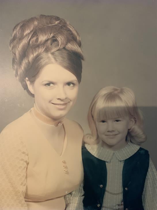 A smiling woman and a young girl pose in 1970s vintage clothing.