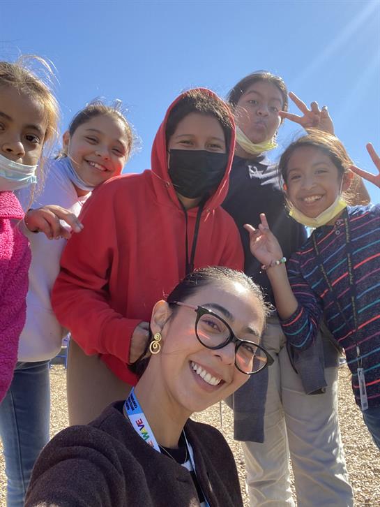 Children and an adult smile and pose for a fun selfie during a bright day in a park.