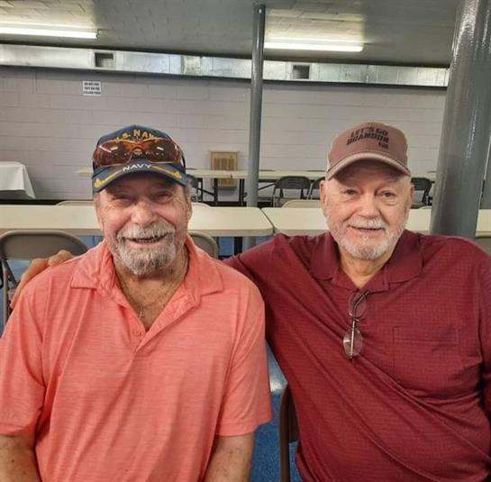 Elderly men enjoy each other's company at a community hall, showcasing warmth and friendship.