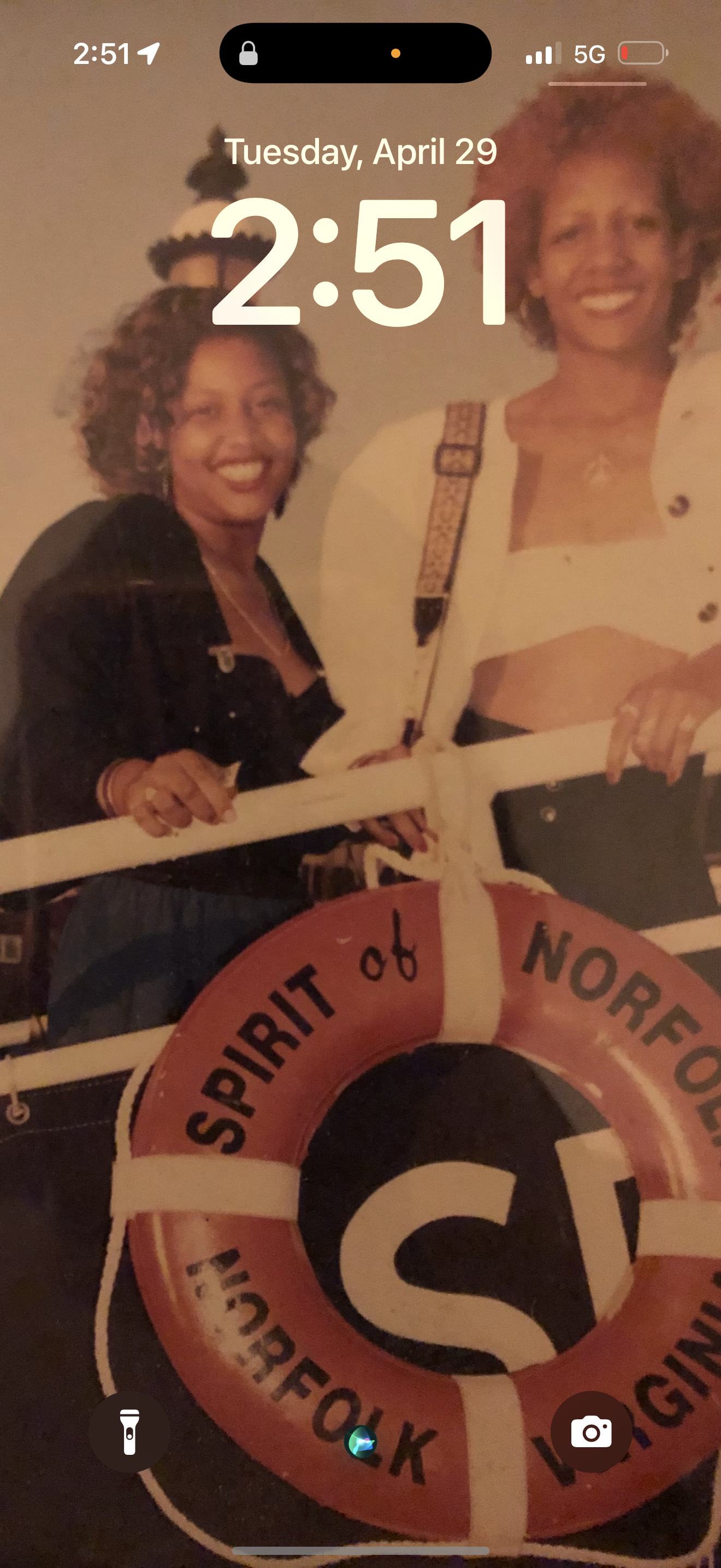 Two friends smile and pose on a boat in Norfolk with a life ring in view.