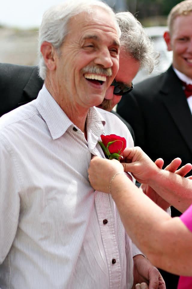A man smiling and holding a rose