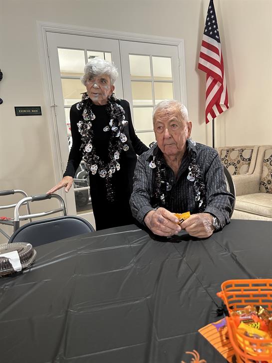 An elderly couple interacts at a community center, showcasing companionship and warmth.