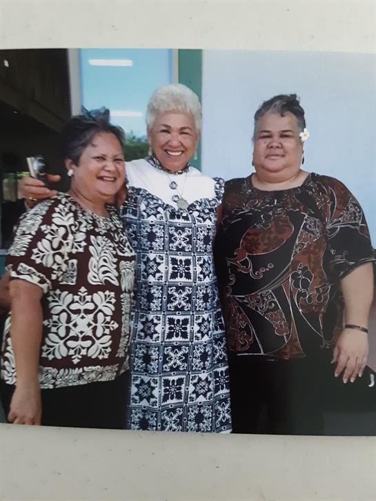 Three women pose happily in colorful traditional outfits during a joyful cultural event.