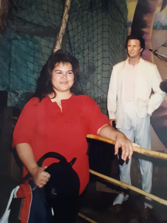 A woman in a red outfit stands next to a life-size figure in a fun setting.