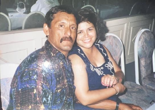 A couple poses happily together, sharing smiles at a social event in a warm atmosphere.