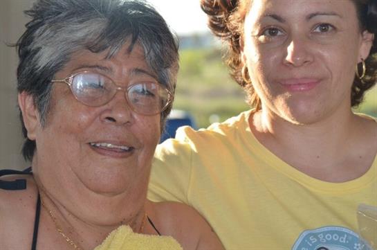 Two women smile happily while spending time together in a warm outdoor setting filled with joy.