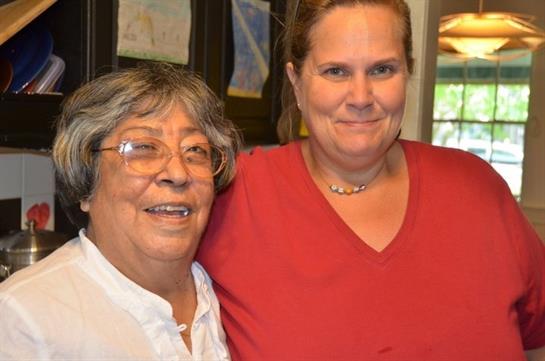 Joyful atmosphere as two women share a warm moment in a kitchen filled with cheerful decor and art.